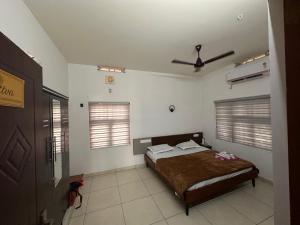 a bedroom with a bed and two windows at Niramaya Heritage Homestay in Kottayam