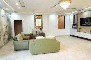 a living room with a couch and chairs and a tv at Hotel Pujari in Khātu