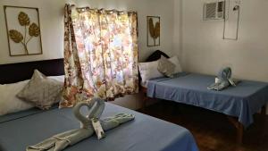 two beds in a room with towels on the tables at Hidden Paraiso Resort in Puerto Galera
