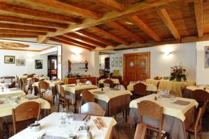 a restaurant with white tables and chairs and wooden ceilings at Hotel Pineta in Ponte di Legno