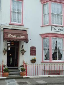 a white building with a red fence in front of it at Taormina Guest House in Tenby