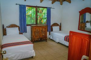 a bedroom with two beds and a window and a mirror at Thermal Paradise Villa in Caluco