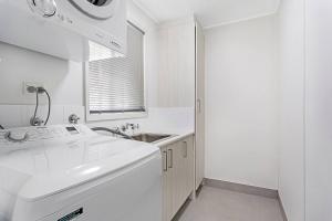 a white kitchen with a sink and a sink at Barefoot Bungalow in Nelson Bay +7 photos