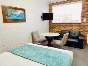 a room with a bed and a table and a couch at Kinross Inn in Cooma