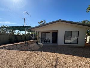 a small white house with a table in front of it at Pandora Place in Lightning Ridge