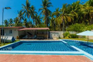a swimming pool in front of a villa with palm trees at Ocean Paradise in Barra de Santiago