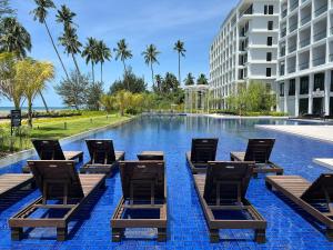 a swimming pool with lounge chairs and a building at Roxy Beach Apartment, Sematan, Sarawak in Sematan