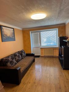 a living room with a couch and a large window at 2 istabu dzīvoklis in Aizkraukle
