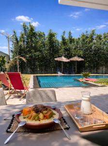 a plate of food on a table next to a pool at Villa de luxe piscine chauffée & Jacuzzi & Petit déjeuner in Fez