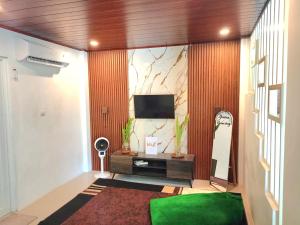 a living room with a television and a green rug at Yustien Homestay Jogja 3 Bedroom - Entire House in Bantul