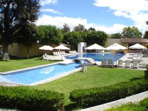 a swimming pool with lawn chairs and umbrellas at Casa Cantarranas in Tehuacán