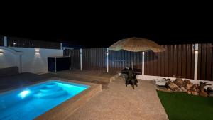 a swimming pool with a table and an umbrella at Serene Private Villa Kangar in Kangar