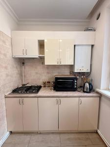 a kitchen with white cabinets and a black microwave at Comfortable zone in Yerevan