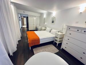 a white bedroom with a bed and a dresser at Casa Ema Azuga in Azuga