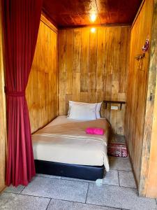 a bed in a wooden room with a red curtain at Chakra Tavern in Bedugul