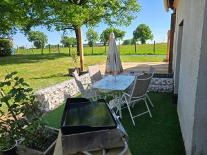 a patio with a table with an umbrella and chairs at maison volet rouge in Devay