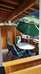 a table and chairs with a green umbrella on a boat at Ferienwohnung Himler in Stumm