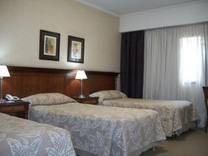a hotel room with two beds and two nightstands at Tucuman Center Suites&Business in San Miguel de Tucumán