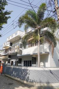 a palm tree in front of a white building at Orange valley Town Residency in Trivandrum