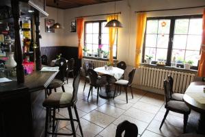 ein Restaurant mit einem Tisch, Stühlen und Fenstern in der Unterkunft Pension & Gasthof Storchennest in Groß Quassow