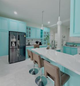 a kitchen with blue cabinets and a large island with chairs at Bluesky Villa Bang Sare in Bang Sare