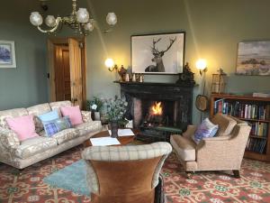 sala de estar con sofá, sillas y chimenea en Mansfield House Hotel, en Hawick