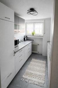 a kitchen with white cabinets and a rug on the floor at Deluxe Apartment Ella in Backnang