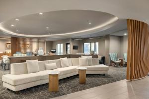 a living room with a white couch and chairs at SpringHill Suites Fresno in Fresno