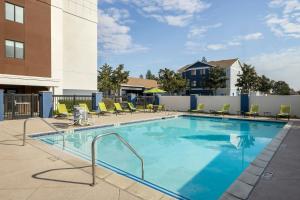 a swimming pool with chairs and a building at SpringHill Suites Fresno in Fresno