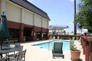 a swimming pool with chairs and tables and a building at Baymont by Wyndham Lewisville in Lewisville