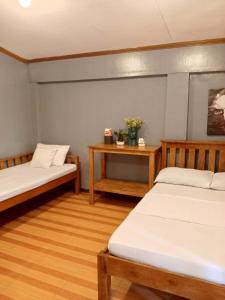 a room with two beds and a table with flowers at Yana's Place in Donsol