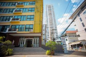a tall yellow building with stairs in front of it at Neo Hotel Pattaya in Jomtien Beach