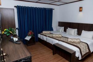 a bedroom with a large bed with a blue curtain at NAT CITY Hotel in Nuwara Eliya