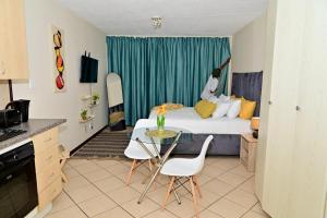 a bedroom with a bed and a table and chairs at Cozy Comfortable Apartment with pool in Pretoria