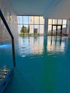 a swimming pool with blue water in a building at Apartament Boho Let's Sea Gąski in Gąski