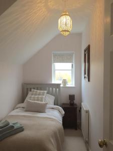 a bedroom with a bed and a chandelier at Pearl Cottage in Blockley