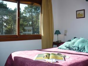 Un dormitorio con una cama con ventana. en Complejo Frente al Golf, en Pinamar