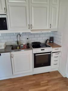 a kitchen with white cabinets and a stove and a sink at Workers Stay - Furnished Housing Umeå Sweden in Klabböle