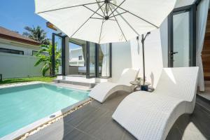 a pool with white chairs and an umbrella at lucky pool villas in Phuket