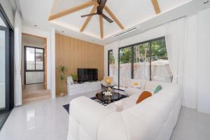 a living room with a white couch and a tv at lucky pool villas in Phuket