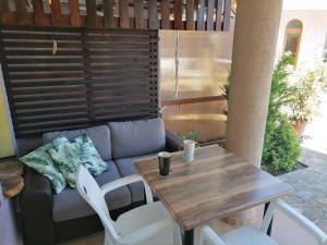 a patio with a wooden table and a couch at Casa do Farol - апартамент с басейн до плажа на къмпинг "Градина" in Chernomorets