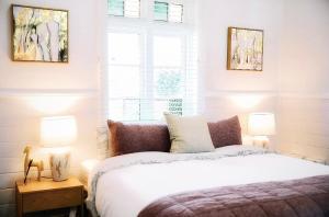 a bedroom with a white bed and two lamps at Maison Macquarie in Dubbo