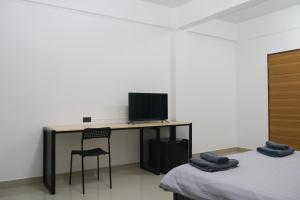 een kamer met 2 bedden en een bureau met een televisie bij Baan Mai Guest House in Bangkok