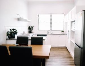 a white kitchen with a wooden table and chairs at Maison Macquarie in Dubbo