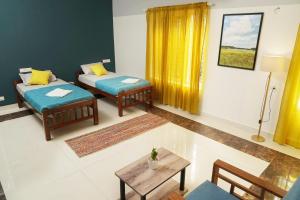 a living room with two beds and a table at Orange valley Town Residency in Trivandrum +30 photos