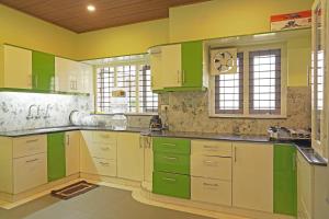 a kitchen with green and white cabinets and windows at Orange valley Town Residency in Trivandrum