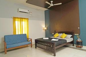 a bedroom with a bed and a blue chair at Orange valley Town Residency in Trivandrum