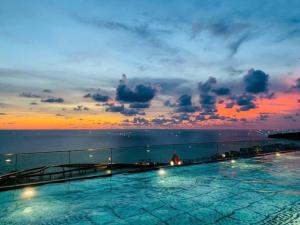 a swimming pool on top of a building with a sunset at ELIO PHÚ QUỐC - Hillside Residence in Phú Quốc