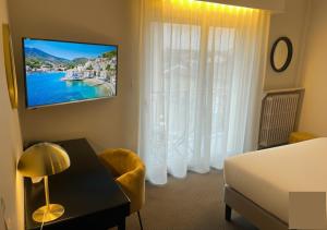 a living room with a bed and a tv and a table at Cit'Hotel Logis De Brou, Bourg en Bresse RENOVE EN 2026 in Bourg-en-Bresse