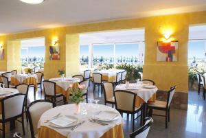 um restaurante com mesas e cadeiras com toalhas de mesa brancas em Hotel Strand em Marina di Montenero